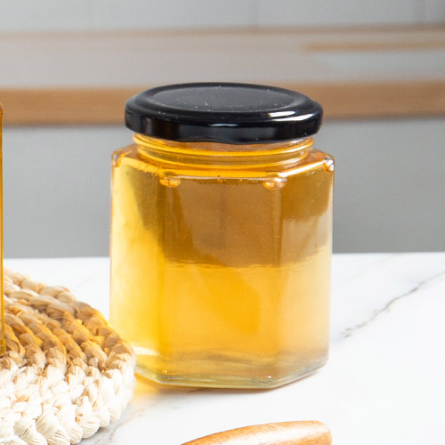 barattolo di miele esagonale in vetro con coperchio ad aletta